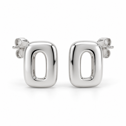 [metal:white-gold] Ilorine Arc-Window Studs — front — Matching pair of small thick polished rounded-rectangle metal studs, each has one narrow curved arch-shaped open window through centre. Smooth solid outer perimeter, straight rear posts and butterfly backs. No stones. [catalog-v4]