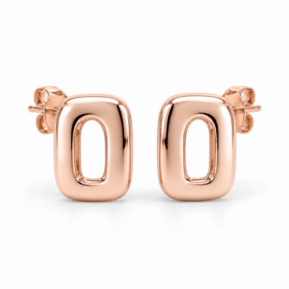 [metal:rose-gold] Ilorine Arc-Window Studs — front — Matching pair of small thick polished rounded-rectangle metal studs, each has one narrow curved arch-shaped open window through centre. Smooth solid outer perimeter, straight rear posts and butterfly backs. No stones. [catalog-v4]