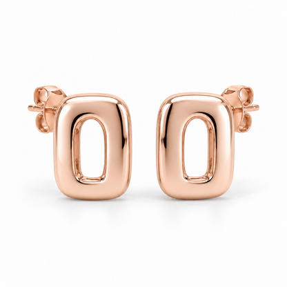 [metal:rose-gold] Ilorine Arc-Window Studs — front — Matching pair of small thick polished rounded-rectangle metal studs, each has one narrow curved arch-shaped open window through centre. Smooth solid outer perimeter, straight rear posts and butterfly backs. No stones. [catalog-v4]