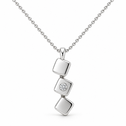 [metal:white-gold] Iserelle Offset Tile Necklace — front — Three small solid polished rounded-square metal tiles in a stepped diagonal cascade, hinged by tiny concealed links, each tile rotated slightly differently. Middle tile alone has one small flush-set round diamond. Fine cable chain through top tile bail. [catalog-v4]