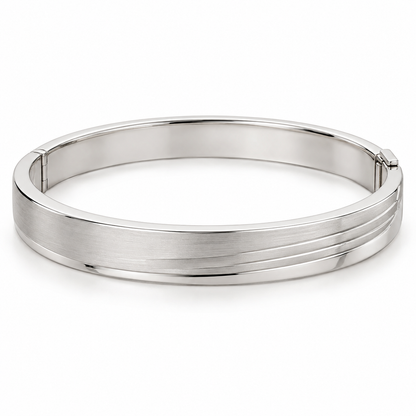 [metal:white-gold] Lorisse Offset-Step Bangle — front — Closed oval hinged bangle, broad flat satin top with three shallow parallel stepped terraces offset toward one edge, polished smooth borders, discreet side hinge and opposite box clasp. Steps are metal surface levels, not multiple separate bangle bands. No stones. [catalog-v4]