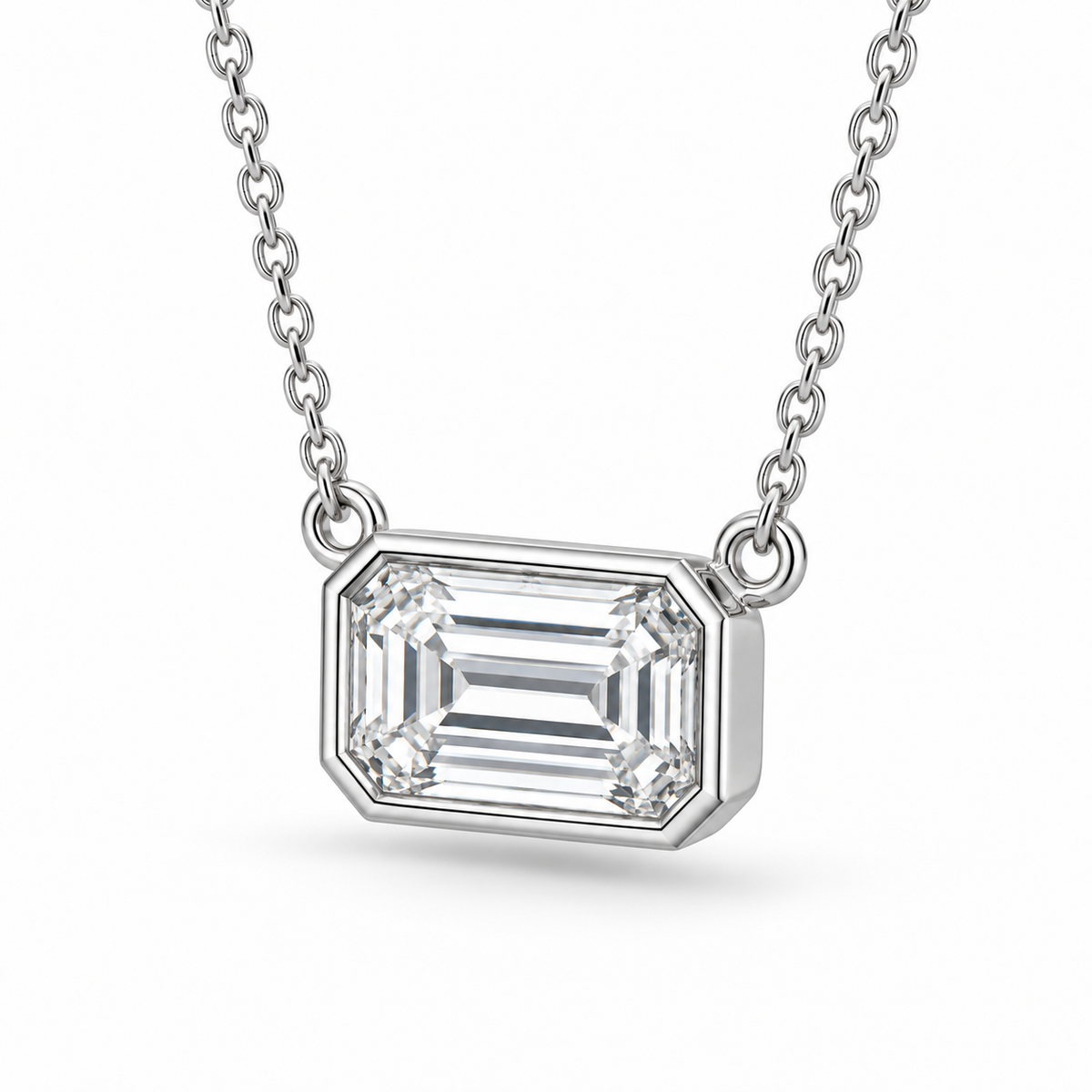 [metal:white-gold] Odette Emerald Pendant — three-quarter — East-west emerald-cut bezel pendant, oblique studio view [catalog-v4]